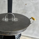 Chapa de ferro com tampa redonda e alça amarela para fogão a lenha