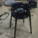 Fogão industrial a gás com estrutura metálica preta e três pernas em chão de cimento