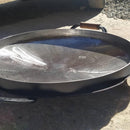 Disco de arado de metal com alça de madeira em ambiente externo de piso concreto e pedrinhas