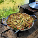 Preparação de arroz frito com legumes e queijo em panela grande sobre fogareiro a gás em ambiente ao ar livre